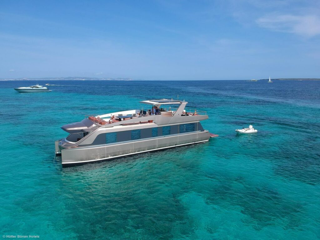 Luftaufnahme einer silberfarbenen Yacht, die als Katamaran gebaut ist.