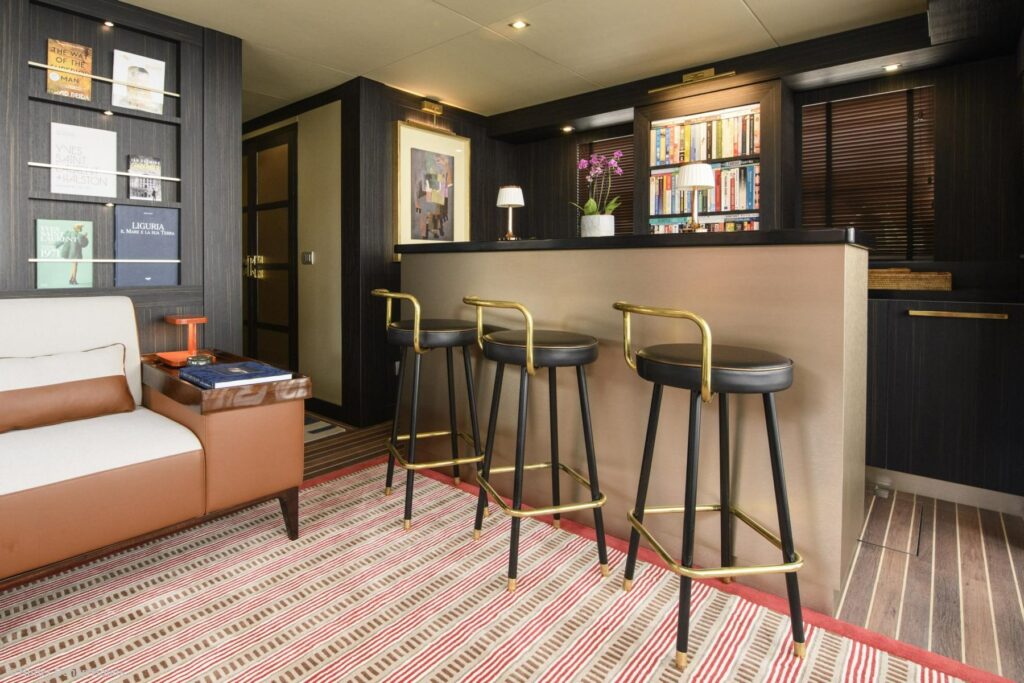 Drei schwarze Barhocker mit goldenen Stilelementen stehen an einer modernen Bar.