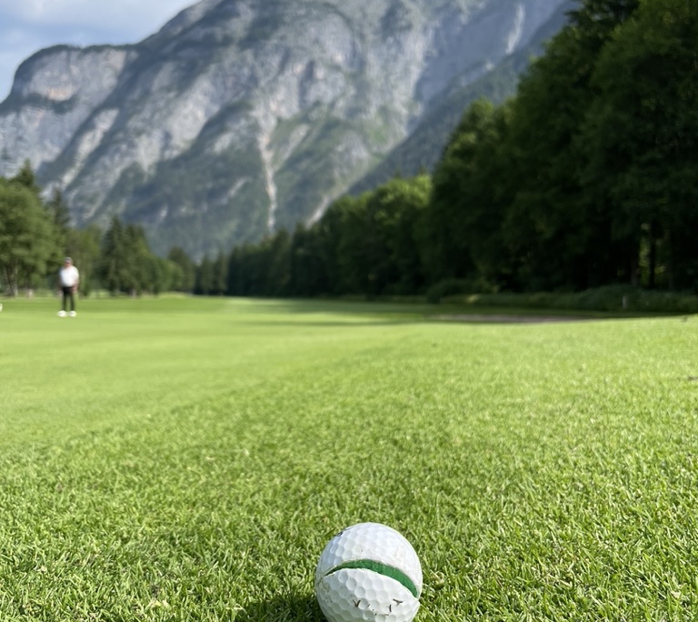 Defekter Golfball vor Bergkulisse des Golfclub Gut Brandlhof