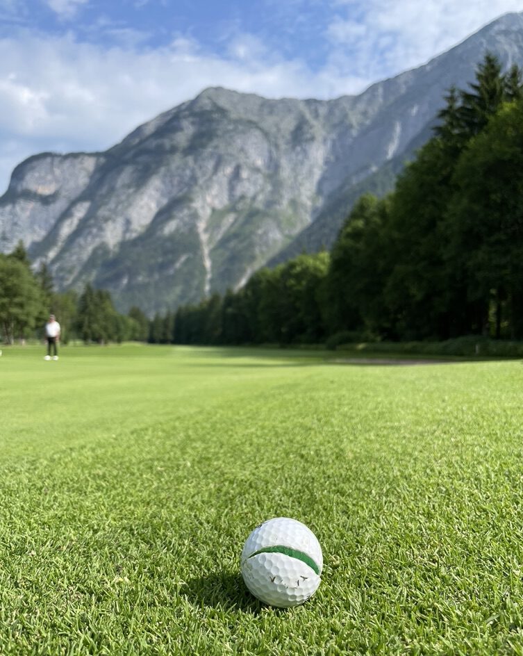 Defekter Golfball vor Bergkulisse des Golfclub Gut Brandlhof