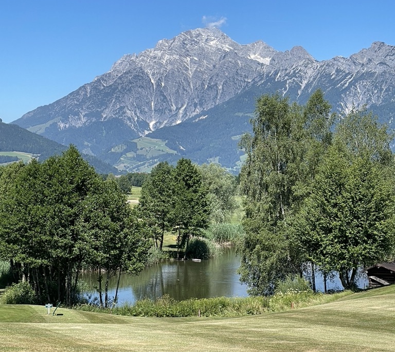 Blick auf einen See mit dahinterliegenden Alpen im Golfclub Urslautal