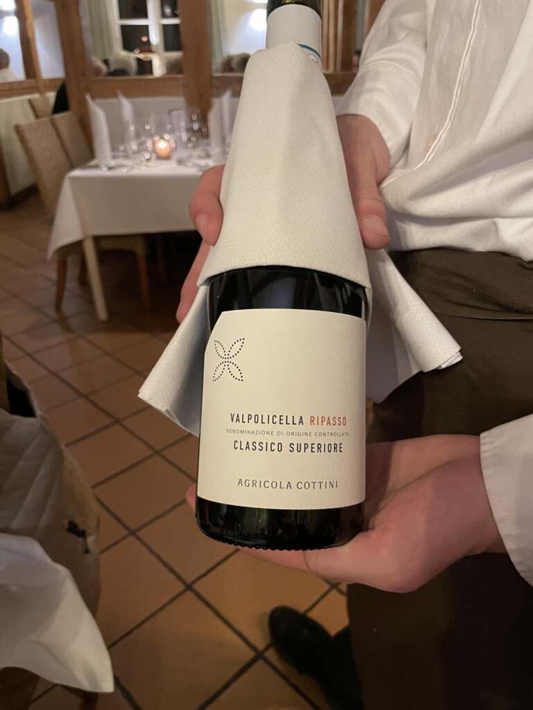 Kellner zeigt eine Flasche des 2018er Valpolicella Ripasso Classico Superiore DOC „Agricola Cottini“ aus dem italienischen Venetien