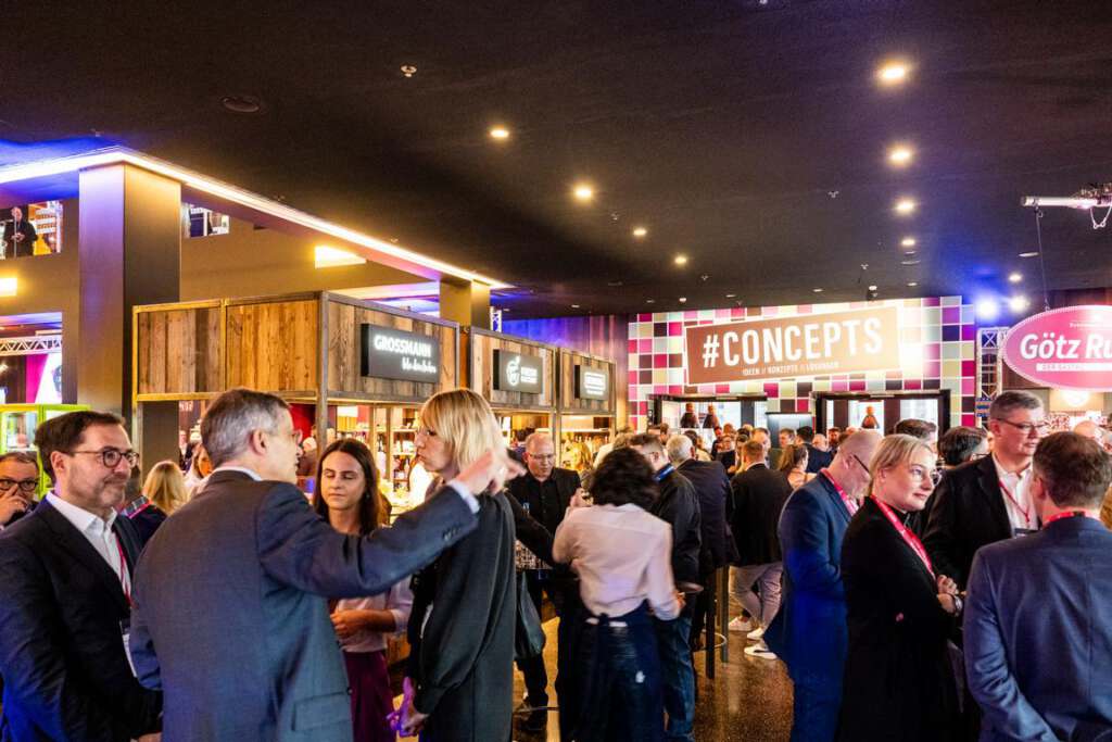 Bei einer gut besuchten Indoor-Networking-Veranstaltung der Gastro Vision in Hamburg kamen Fachleute aus Gastronomie und Hotellerie in Hamburg zusammen und tauschten sich aus. Im Hintergrund war neben verschiedenen Gastro Vision-Imbissständen ein Schild mit der Aufschrift „#CONCEPTS“ zu sehen.