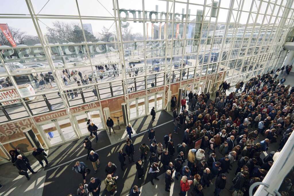 Im Atrium des Eingangsbereiches der Messe Hamburg versammelt sich eine große Menschenmenge, um zur Fachmesse Internorga zu gelangen. Menschen kommen von außen durch mehrere Türen herein.