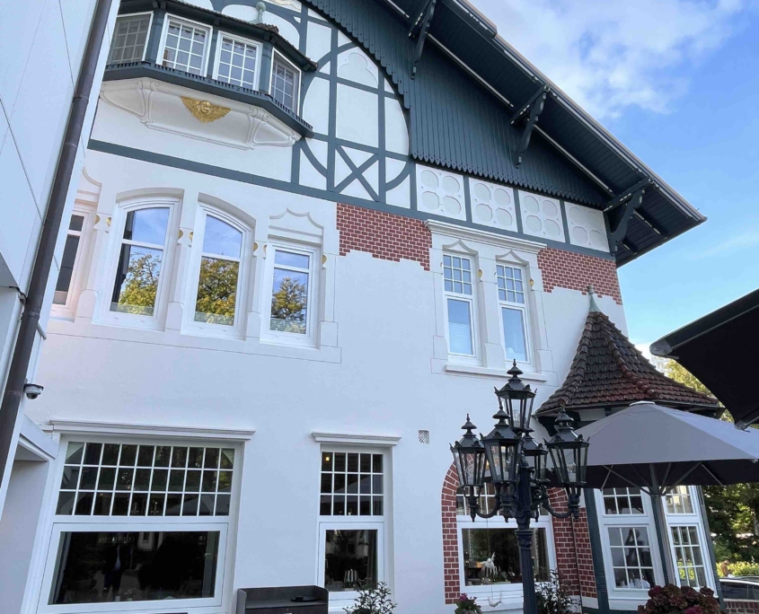 Außenaufnahme eines weißen Hauses im Fachwerkstil, das ein Hotel und ein Restaurant ist.