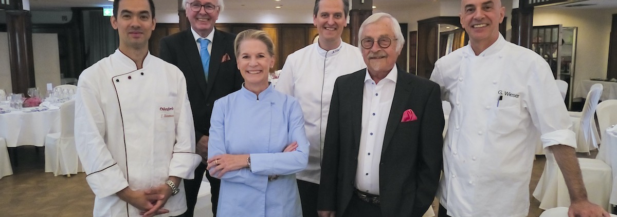 Vier bekannte Köche und zwei Herren in Anzügen lächeln in einem großen Saal in die Kamera. Sie sind das Team zur Eröffnung des 38. Schleswig-Holstein Gourmet Festivals in Pinneberg bei Hamburg.