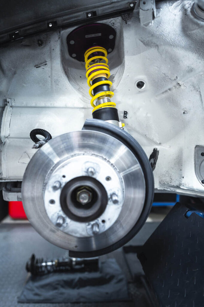 Autofederungssystem mit sichtbarem Gewindestoßdämpfer und Bremsscheibe.