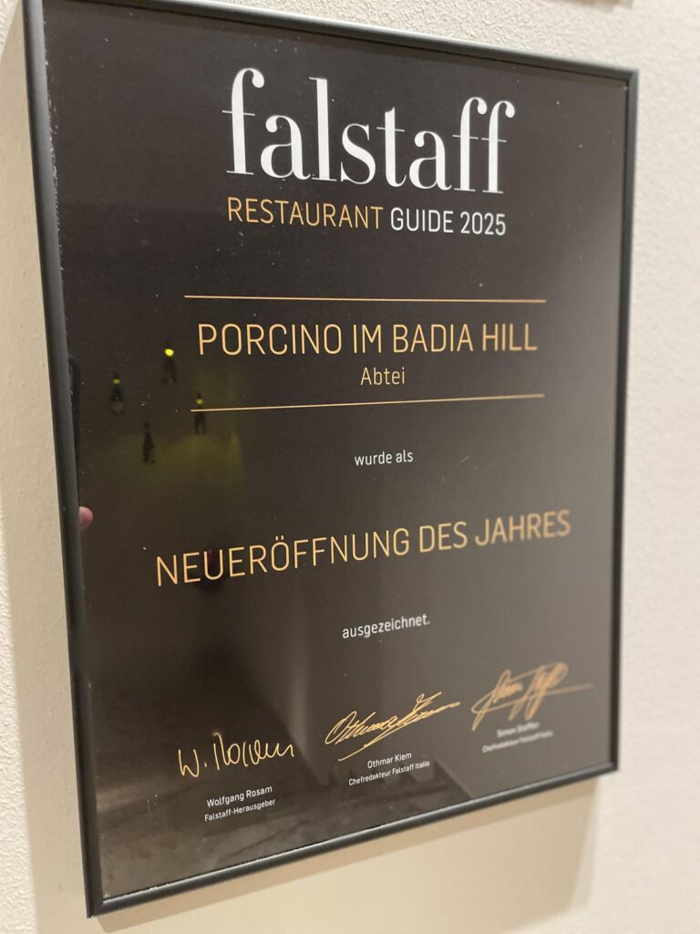 Plakette an einer Wand für den Falstaff Restaurant Guide 2025, der „Porcino im Badia Hill“ als „Neueröffnung des Jahres“ auszeichnet, mit drei Unterschriften unten.