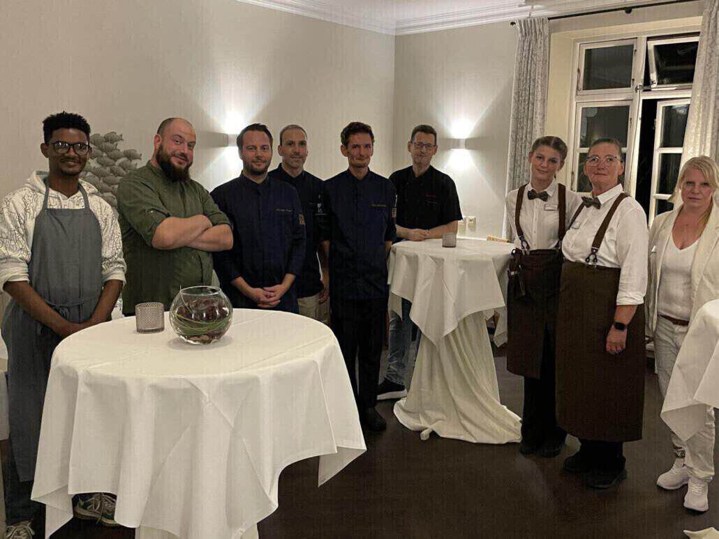 Köche und Kellner stehen nach getaner Arbeit zusammen.