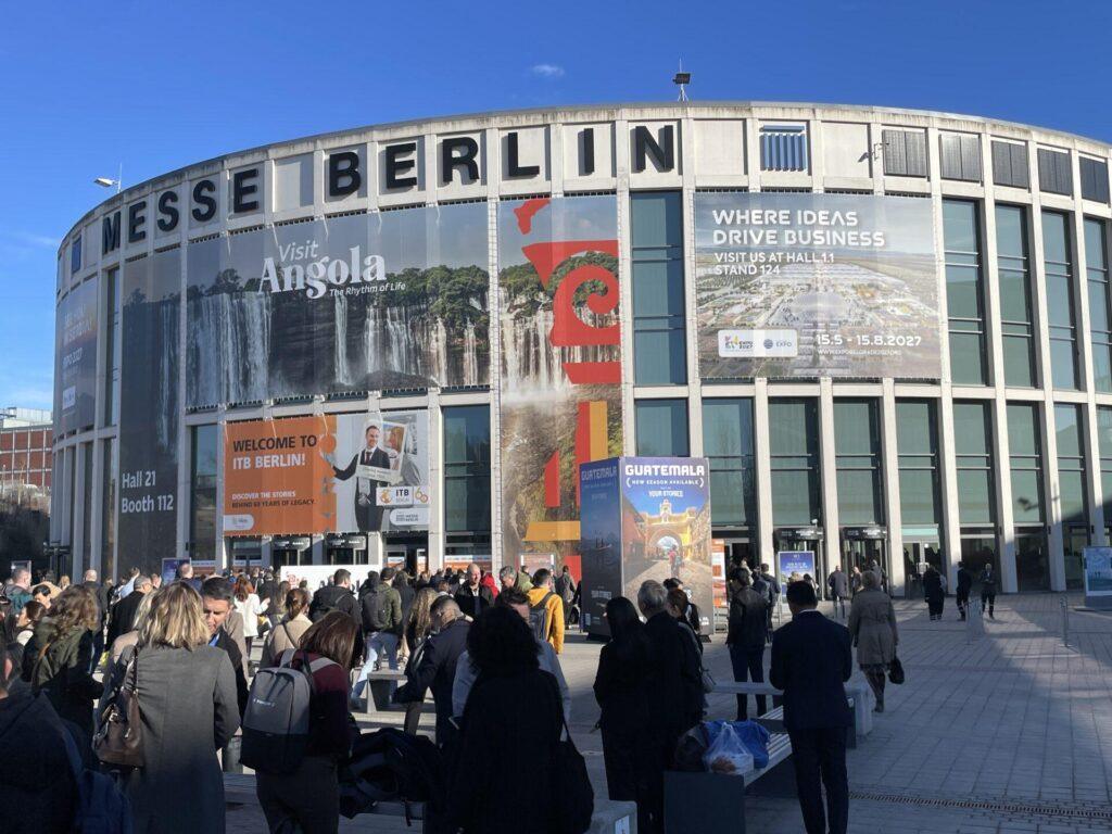 Eine Menschenmenge versammelt sich im März 2026 vor der Eingangshalle der Messe Berlin, die mit großen Bannern für Angola, Guatemala und eine Wirtschaftsveranstaltung in 2027 wirbt.