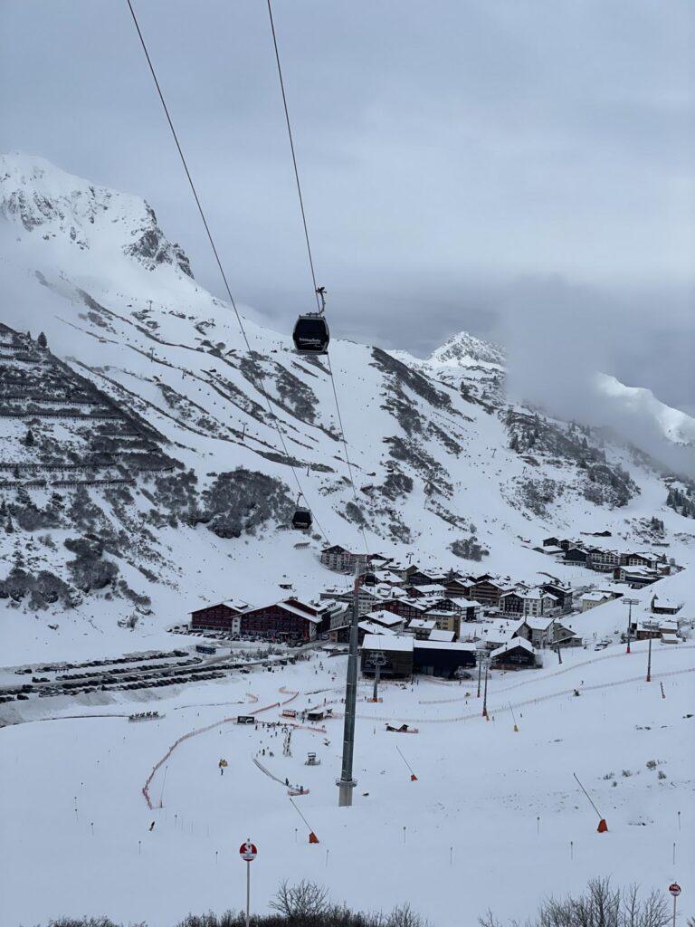 Ein Skigebiet mit schneebedeckten Bergen, einem Seilbahnsystem und mehreren Gebäuden am Fuße der Pisten.